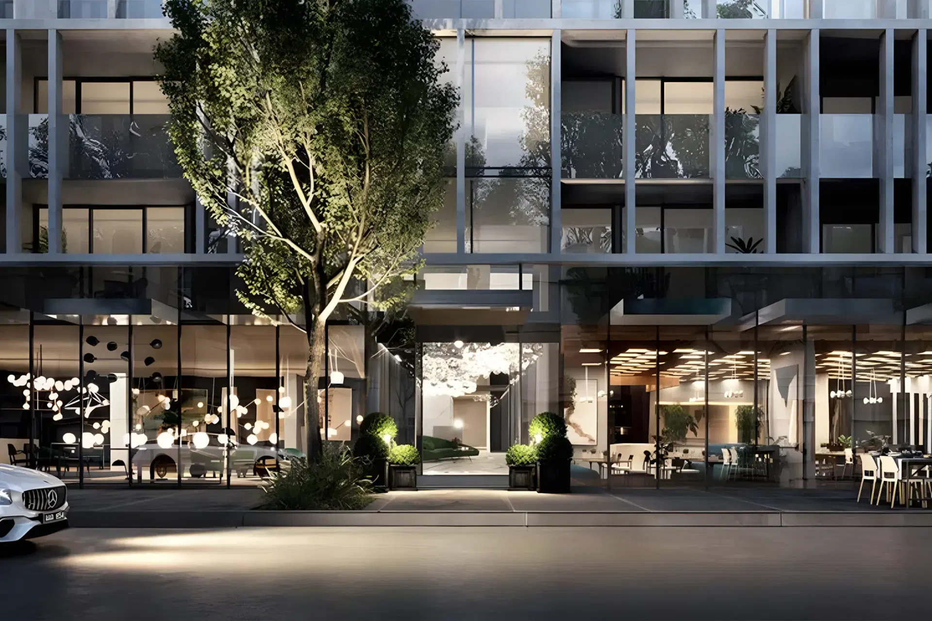 Streetscape of the South Melbourne apartment building at dusk, its lobby and ground-floor tenancies lit from within